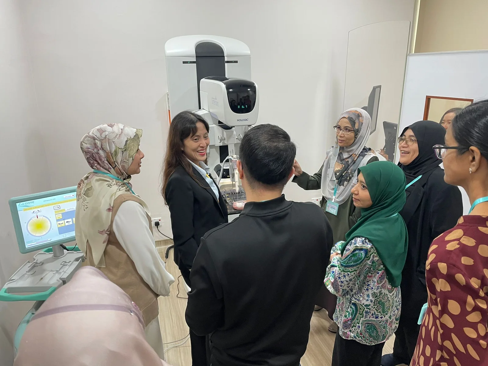 A small group in discussion beside breast imaging equipment.